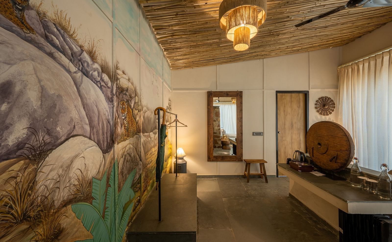 An image of a room with wall paintings, chandelier, ceiling fan, and decorative items - Utsav Camp Sariska