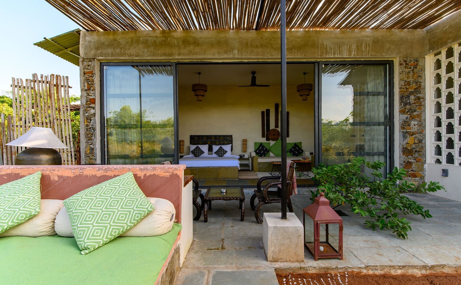 An image of a room with an expansive glass door leading to the outdoor area - Utsav Camp Sariska