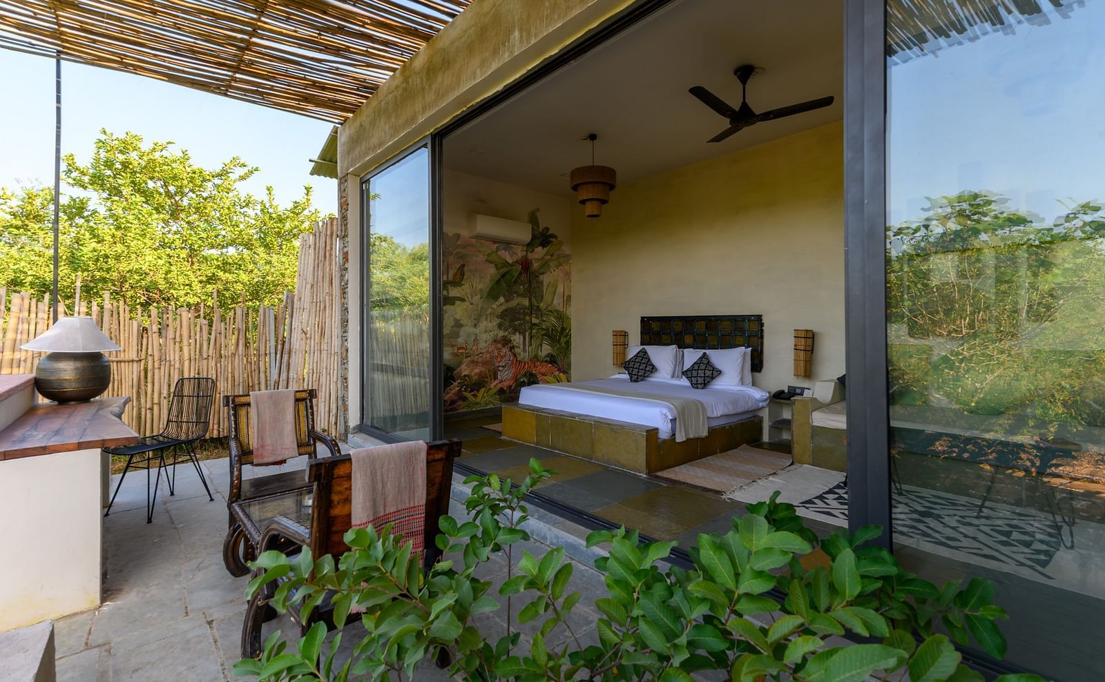 An image of a room with an expansive glass door leading to the outdoor area - Utsav Camp Sariska