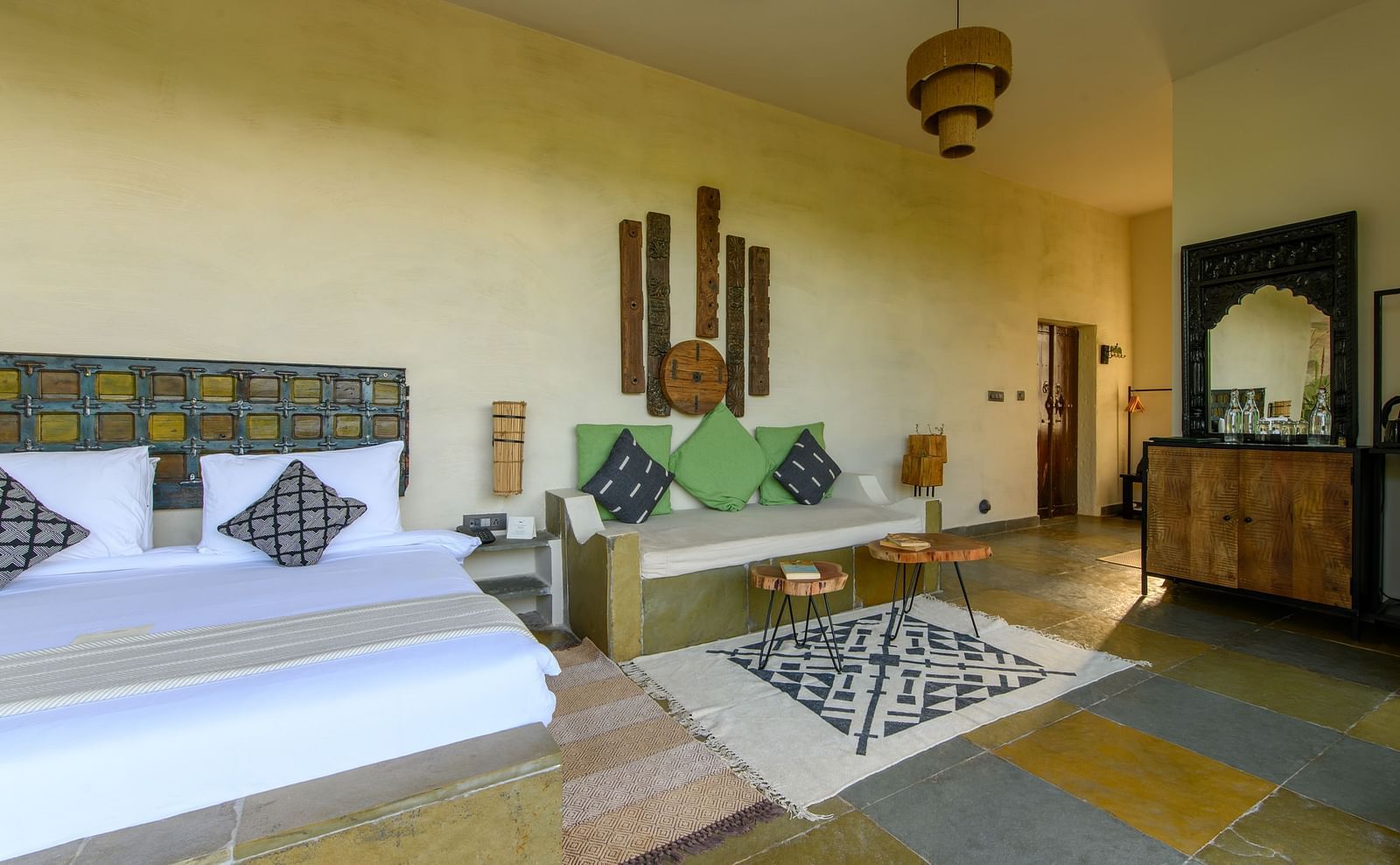 An image of a room with a queen size bed, chandelier, ceiling fan and other decorative items - Utsav Camp Sariska