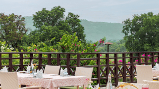 An outdoor dining setup with a table and chairs, offering a scenic view at Aamaghati Wildlife Resort.
