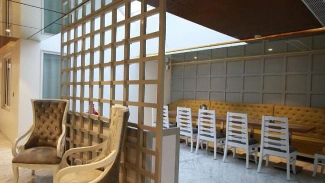 A cosy lounge area with elegant beige chairs, a decorative wooden partition, and contemporary interior design - Hotel Emerald, Chandigarh