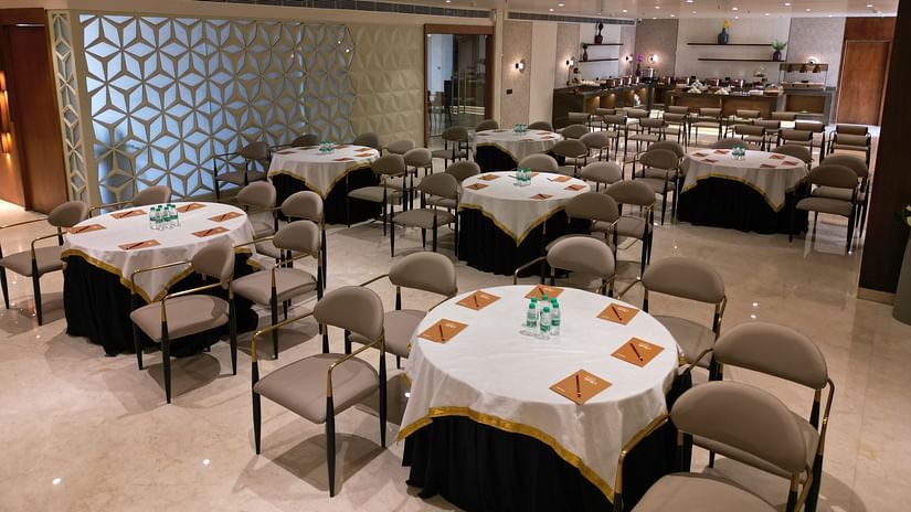 A well-arranged dining area with neatly set tables and chairs, each table covered with tablecloths at Clarks Collection Grand Sapphire, Ajmer.