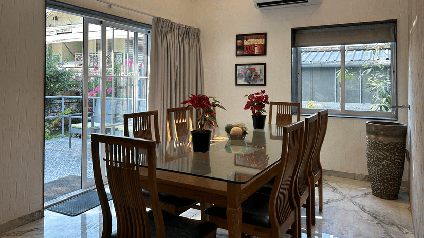 A sophisticated dining area with a polished wooden table, elegant chairs, and large glass windows – Maxxvalue Klub Klass Villa, Lonavala.