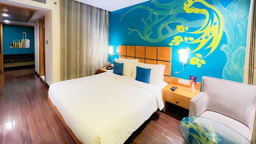 An image of a bedroom with king size bed, bedside table, a sofa, and centre table