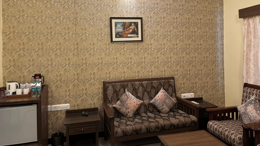 A seating area at Amantra Shilpi Resort, Udaipur with a couch, a small table, and a framed picture.