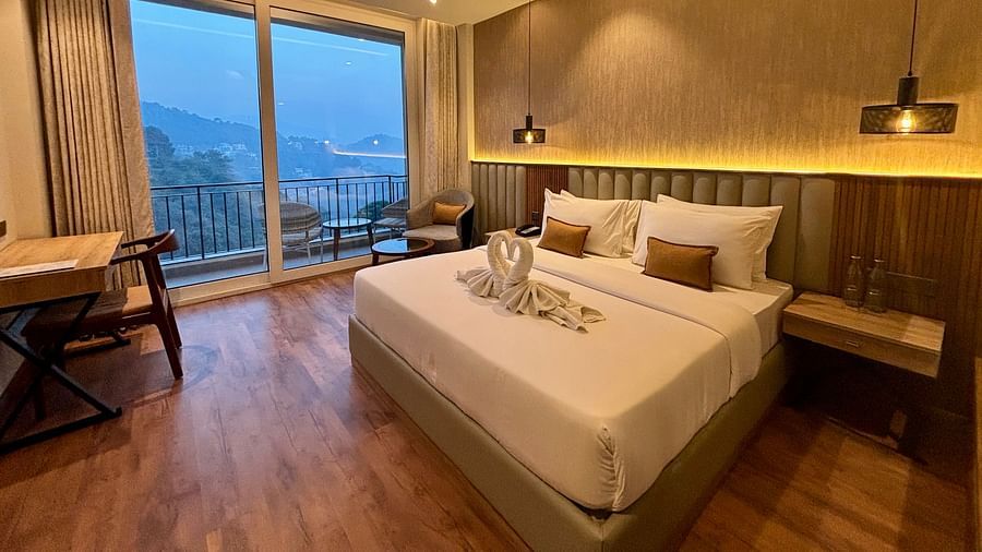 Elegant bedroom with large windows, wooden accents, and a scenic balcony view – ARNISA Boutique Hotel
