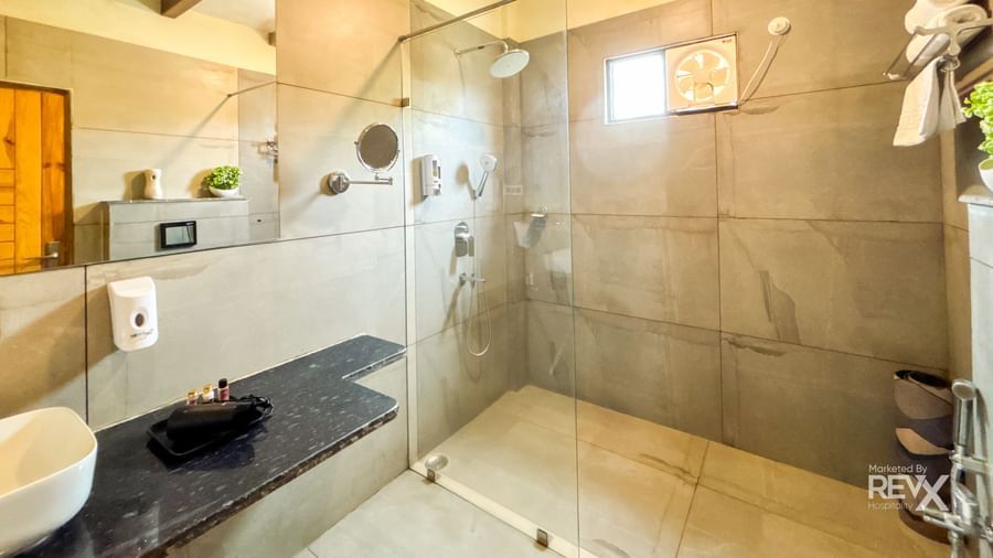 Modern bathroom with glass shower enclosure and sleek fittings at Corbett Nirvana Resort.