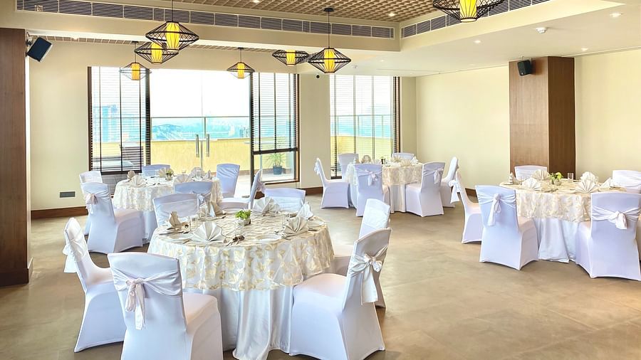 An image of a banquet hall with its seating arrangement and subtle decoration with lighting - Hideaway banquets & Lawns, Greater Noida