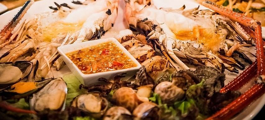A dining table with seafood served with two glass of white wine