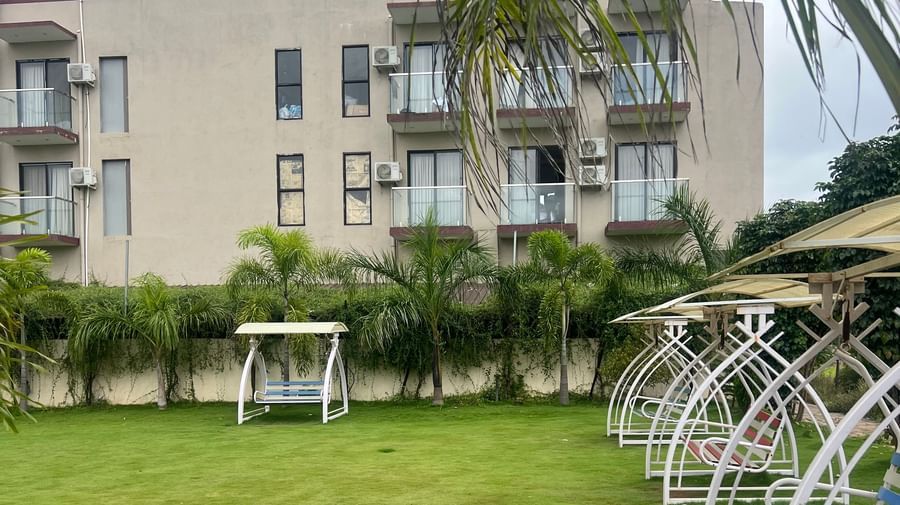 Lawn of Daksh The Valley Resort, Saputara, featuring swings to sit on one side, and the multi-storey resort seen on the other.