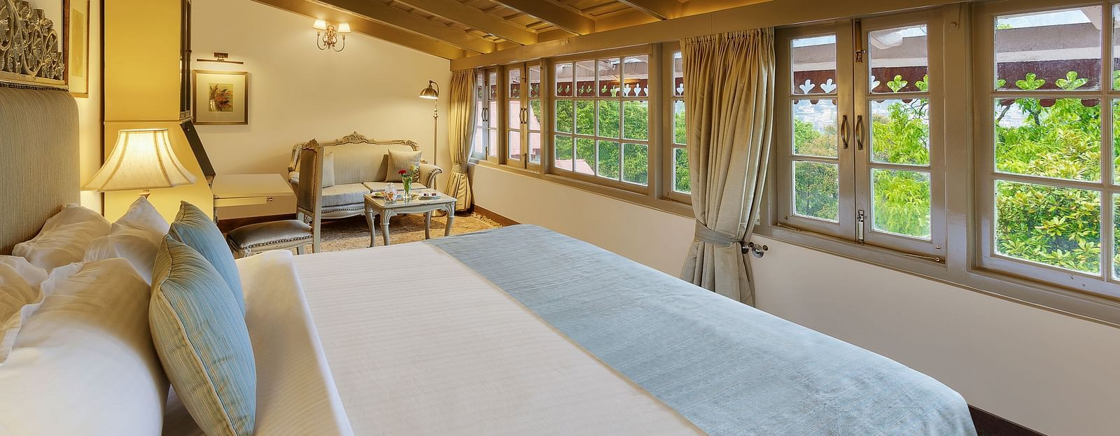 A lush room with cosy decors, king size bed with pillows and soft cushions, wooden ceiling overseeing the mountain views- The Naini Retreat
