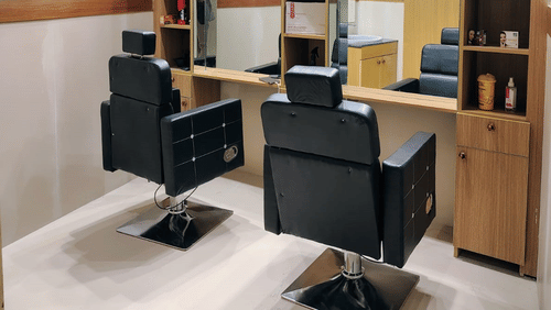 A salon at ABN Sarovar Portico, Jim Corbett featuring two chairs in front of the mirror, and behid the mirrors there are shelves where all the cosmetic products are kept. 