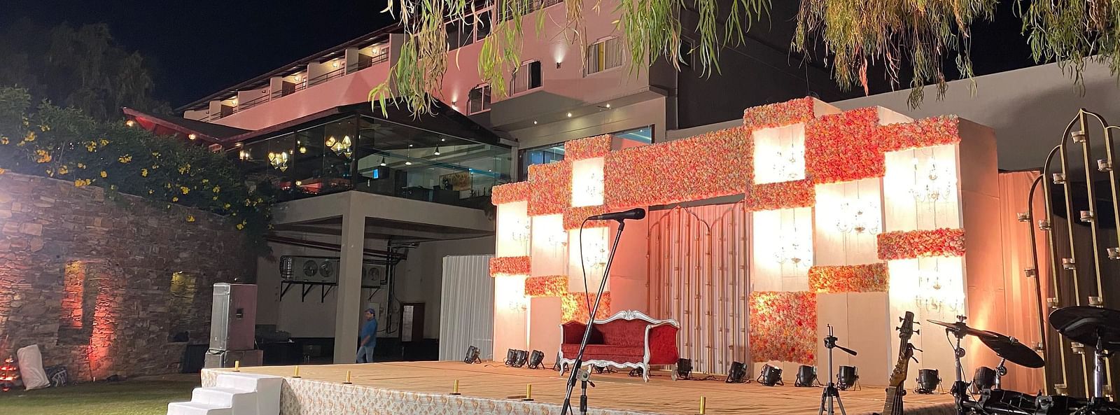 A outdoor stage with lights and decorations arranged within a stone wall backdrop. 