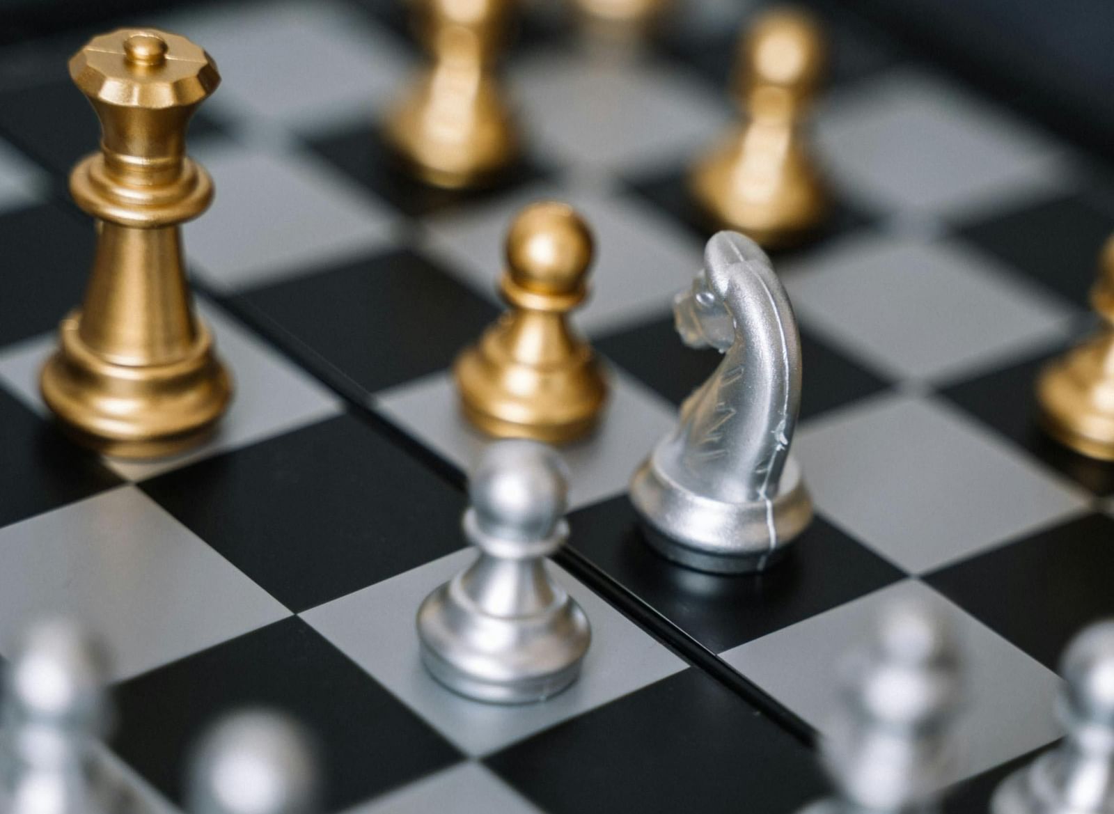 A chessboard with various gold and silver chess pieces.