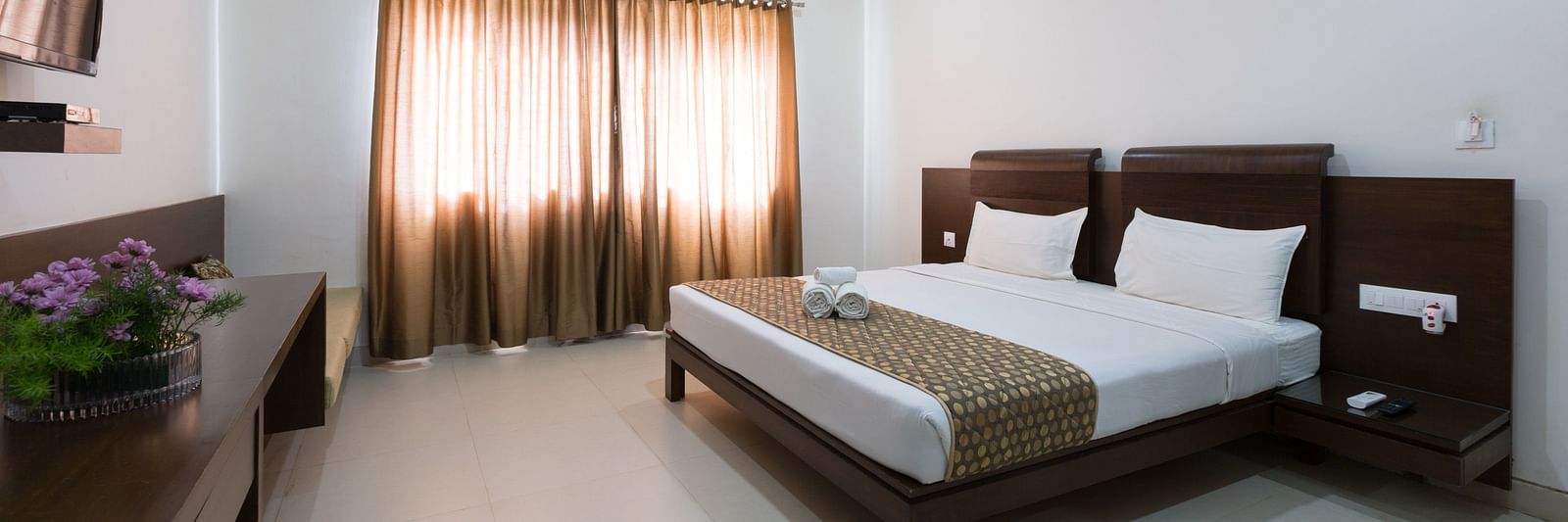 A bedroom with a bed, wooden furniture, and neutral-toned decor under soft lighting - Sanctum Suites BEL Road, Bangalore