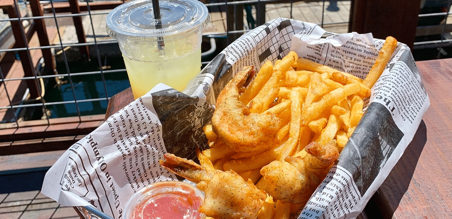 A bunch of fries, and a beverage on a tray on a sunny day