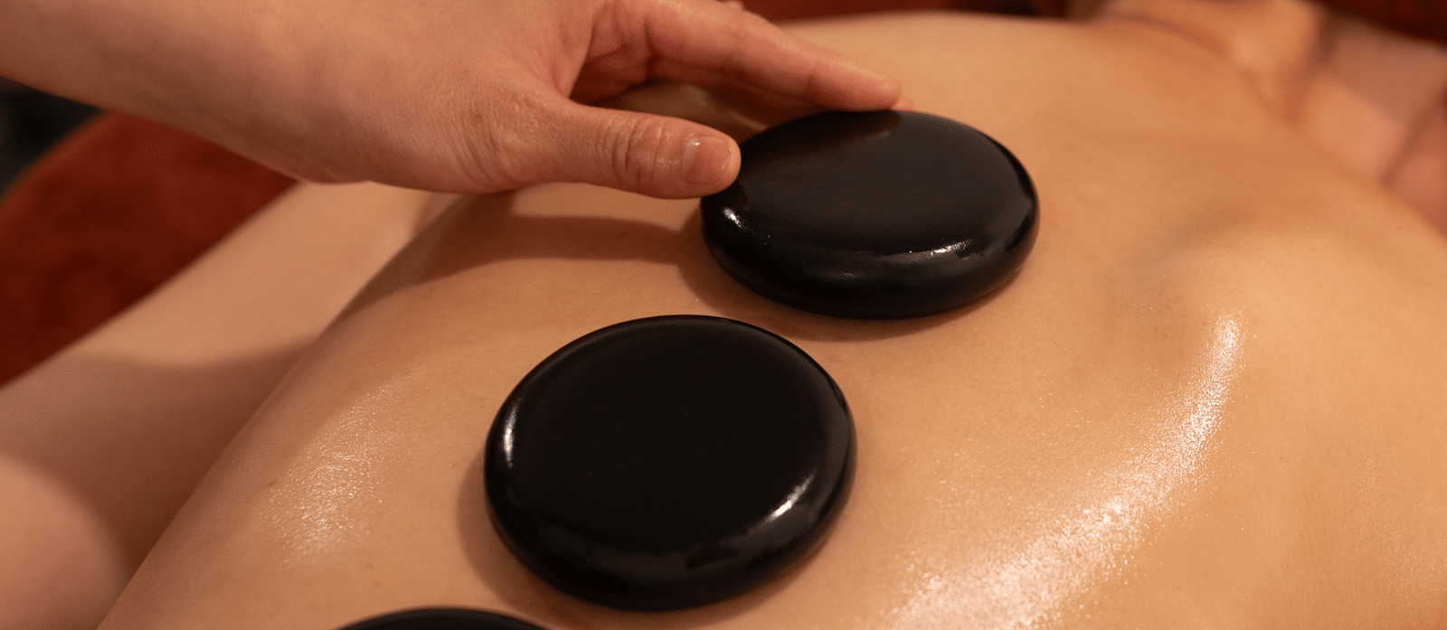 A guest at Alibu Resort Nha Trang laid on his stomach receiving a back massage with oil and round stone like objects.