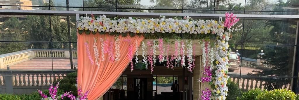 Decorated entrance of the banquet hall at Mayur Retreat, adorned with orange drapes and fresh floral arrangements.