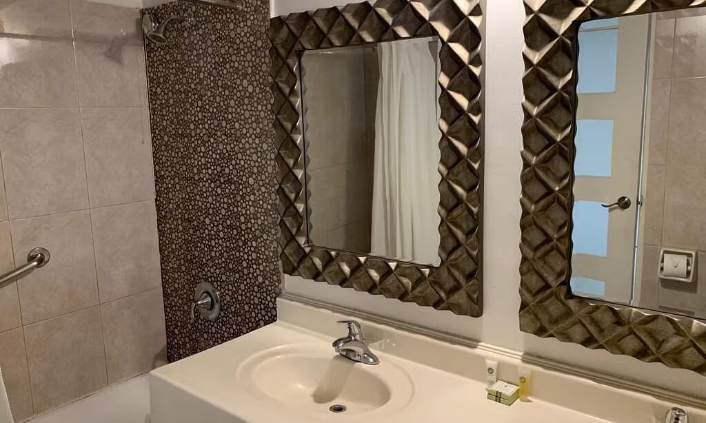 A bathroom with a double vanity, two sinks, and two framed mirrors with textured surrounds | Junior Suite | Altamont Court, Jamaica