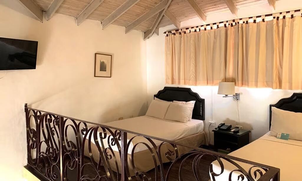 A bedroom with a bed and a decorative railing overlooking another area | Junior Suite | Altamont Court, Jamaica