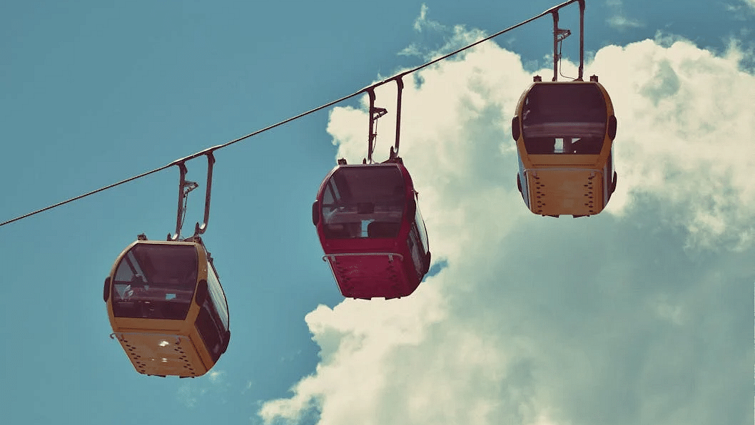 A bright red and yellow ropeway suspended in the sky.