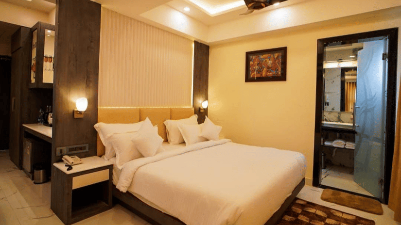 A bedroom showcasing plush bed with pillows, ceiling fan, artwork, and sliding balcony doors.