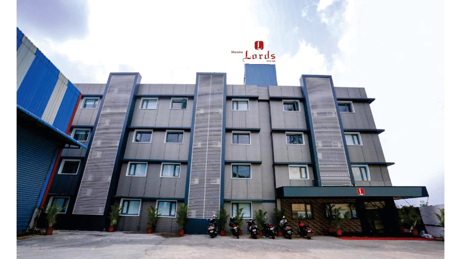 A modern, dark grey hotel building with a red sign.