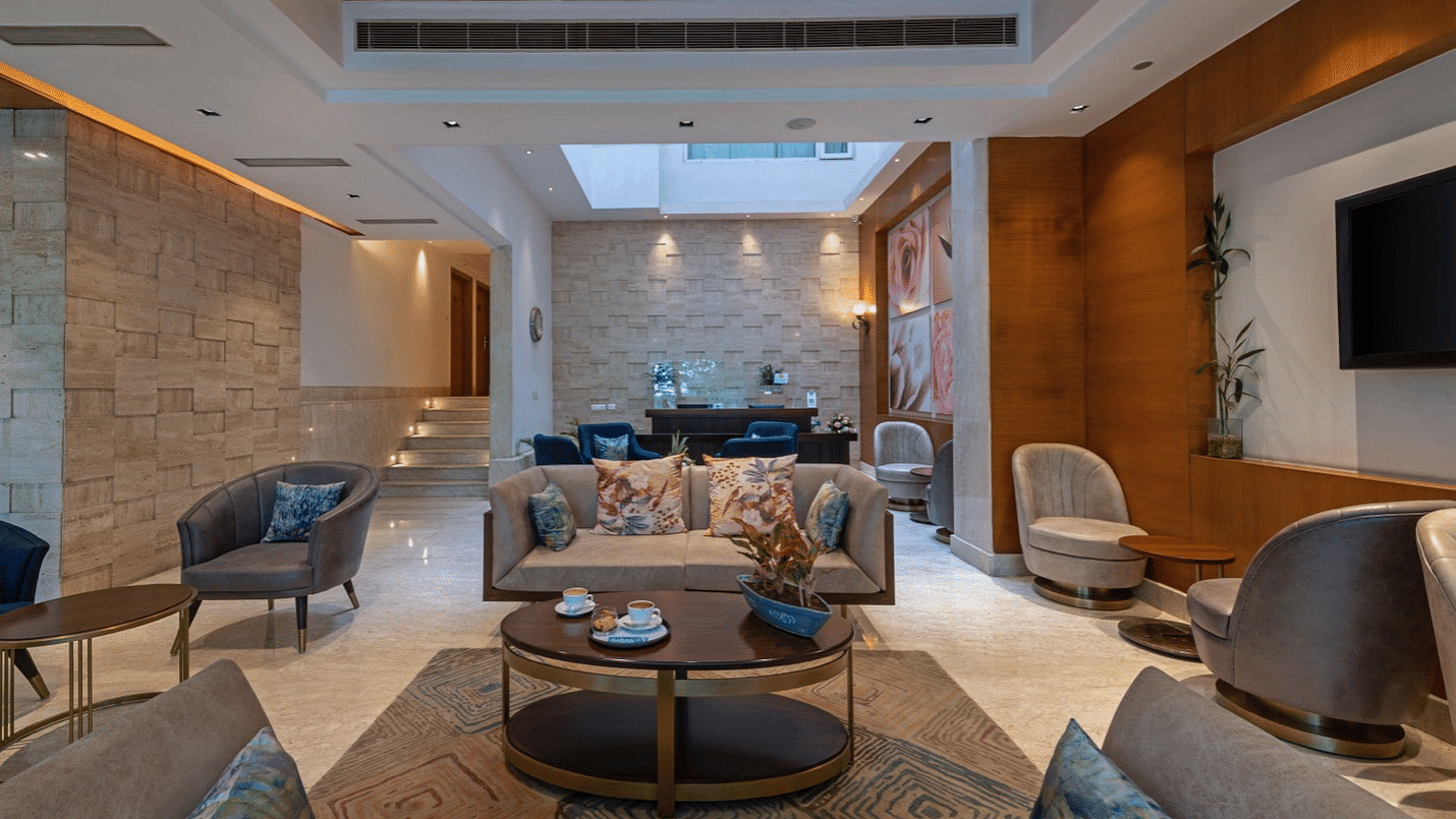 Hotel lobby with modern decor, seating area with armchairs and coffee tables, warm lighting, spacious design.