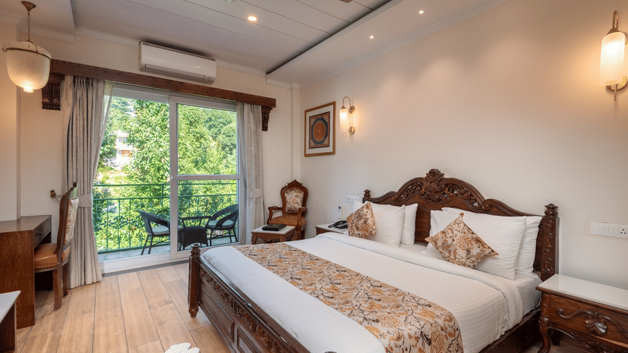 A spacious bedroom with a bed, a desk, and a balcony with outdoor seating at the Quality Inn family suite.