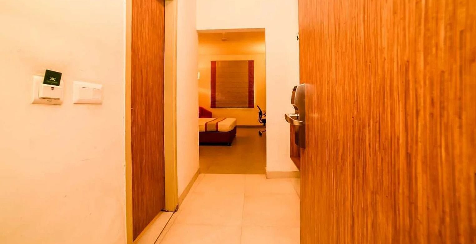entrance of the Max Family Room with a wooden door opening into the corridor of the room - Max Hotel Jabalpur