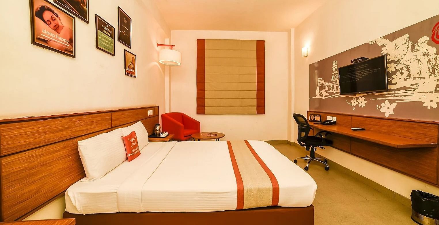 side view image of the queen size bed placed right in front of the wall mounted television - Max Hotel Jabalpur