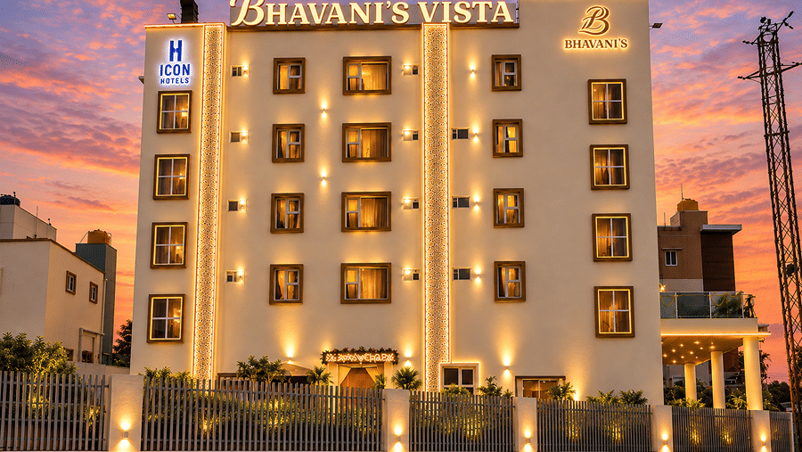 Multi-storey hotel building brightly lit against a dramatic sunset background at Bhavani's Vista By Icon, Hosur. 