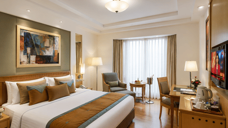 Elegant king room with warm interiors and work desk at Eastlynn Collections HUDA City Centre, Gurugram.