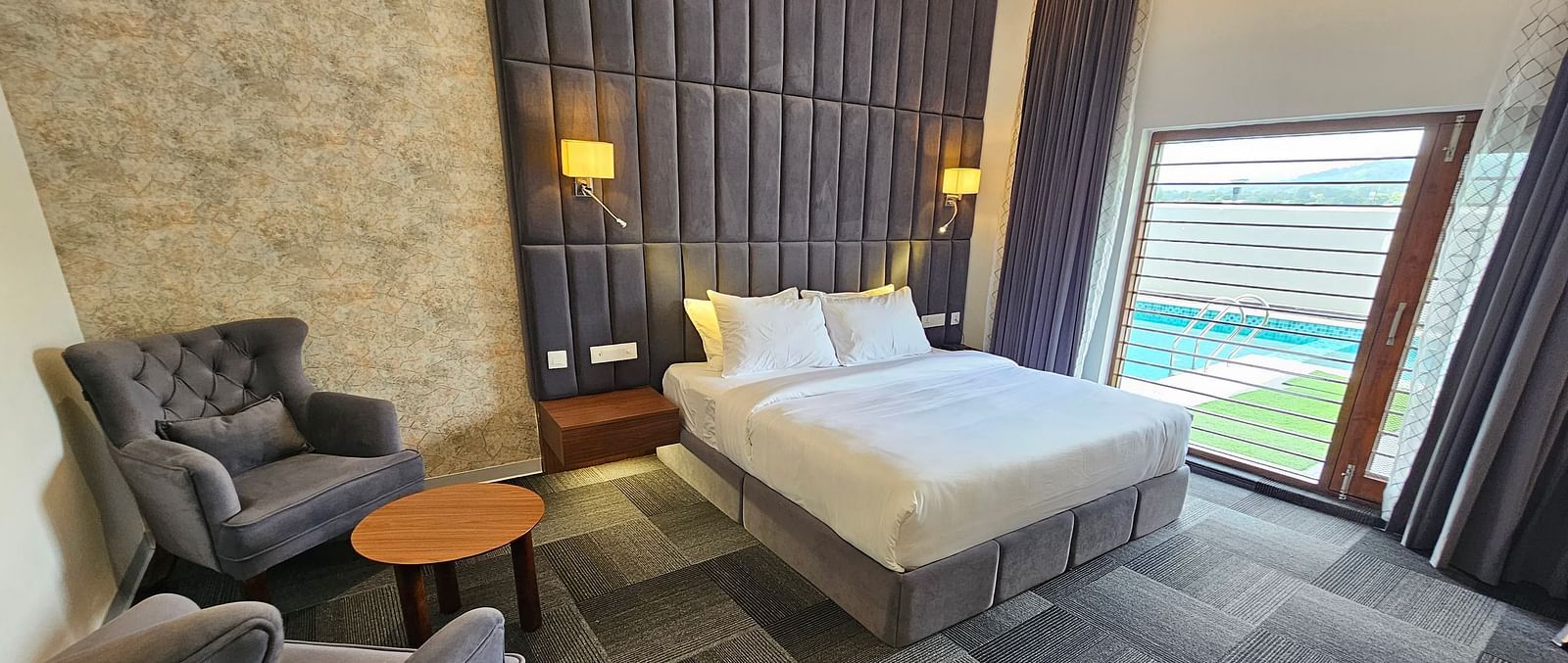 full view image of the premium room at Eminence The Corbett withe a comfortable double bed and huge windows besides it