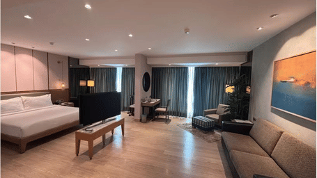 Cosy sitting area at Mirage Hotel with armchairs, desk space, and floor-to-ceiling curtains.