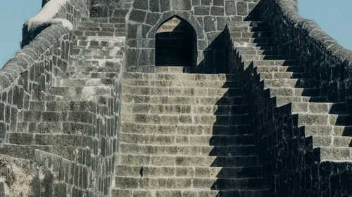 A stone fort structure with stairs leading up to an arched entrance.