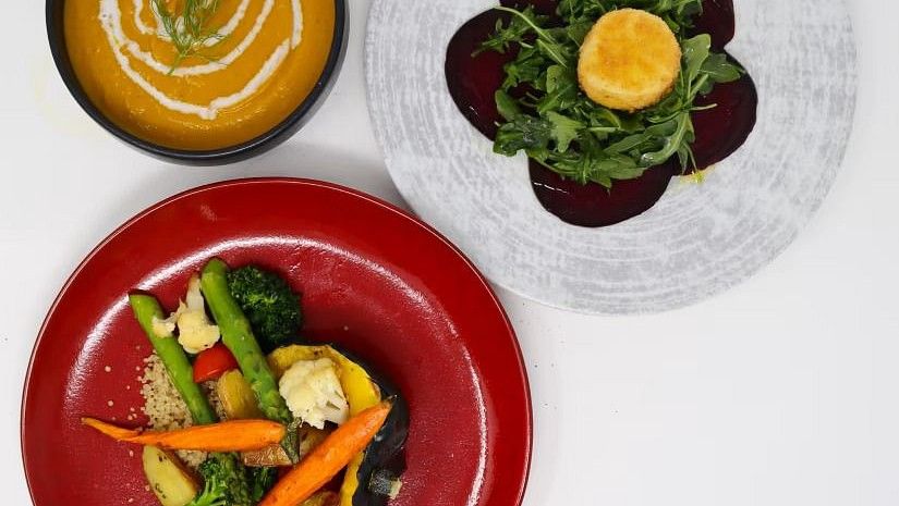 A vibrant, healthy meal with a bowl of soup, a beetroot salad, and a plate of mixed vegetables.