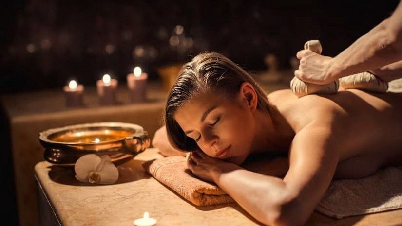 A woman receiving a therapeutic massage with herbal pouches at YO1, Catskills, New York, highlighting holistic wellness treatments.