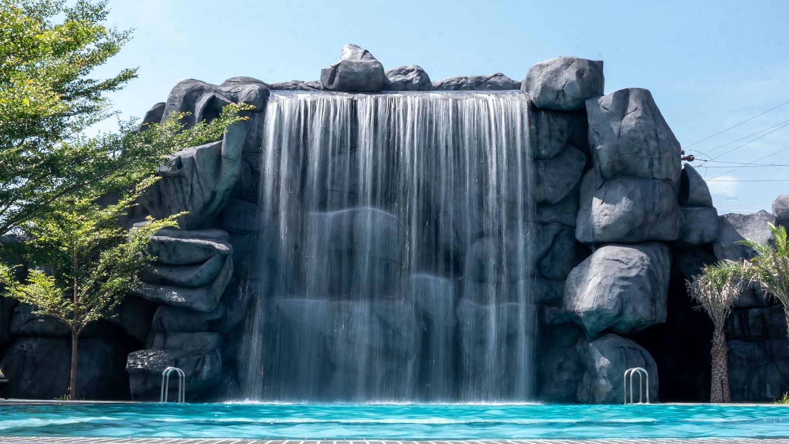 A wide-angle view showcasing a stunning waterfall-like structure with a pool in front, creating the perfect setting for family fun activities.