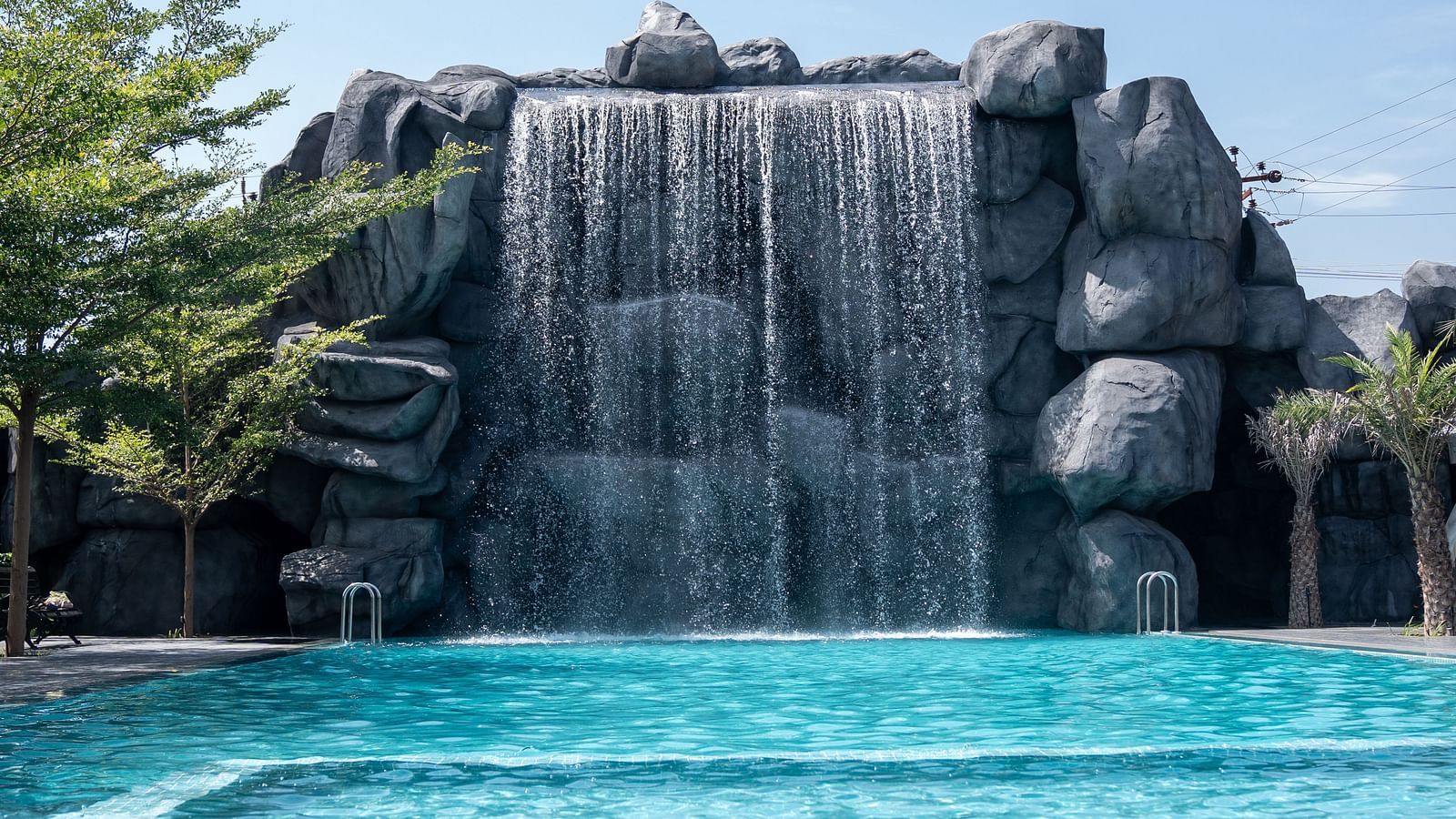 A broad-view capturing a cascading waterfall feature with a pool in front, offering some of the most exciting fun activities in Coimbatore for all to enjoy.