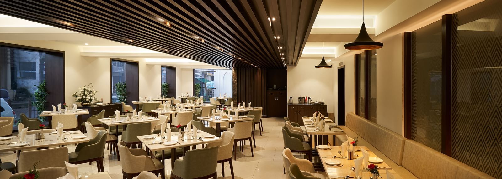 Spacious dining area with tables and chairs on one side, and seats along the wall on the other at The Hamuse Hotel, Kodaikanal.