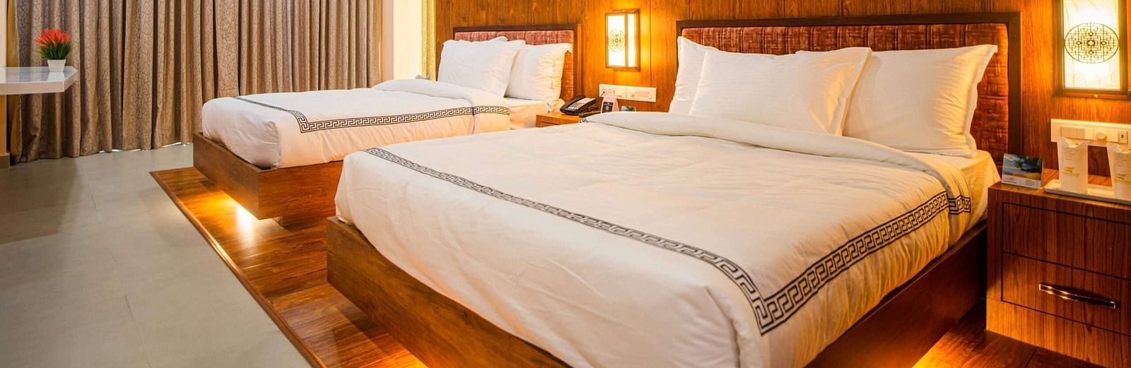 The comfortable rooms at Mansha Palace offer two beds, warm wooden accents, and a strategically placed opening that provides a peek into the bathroom.