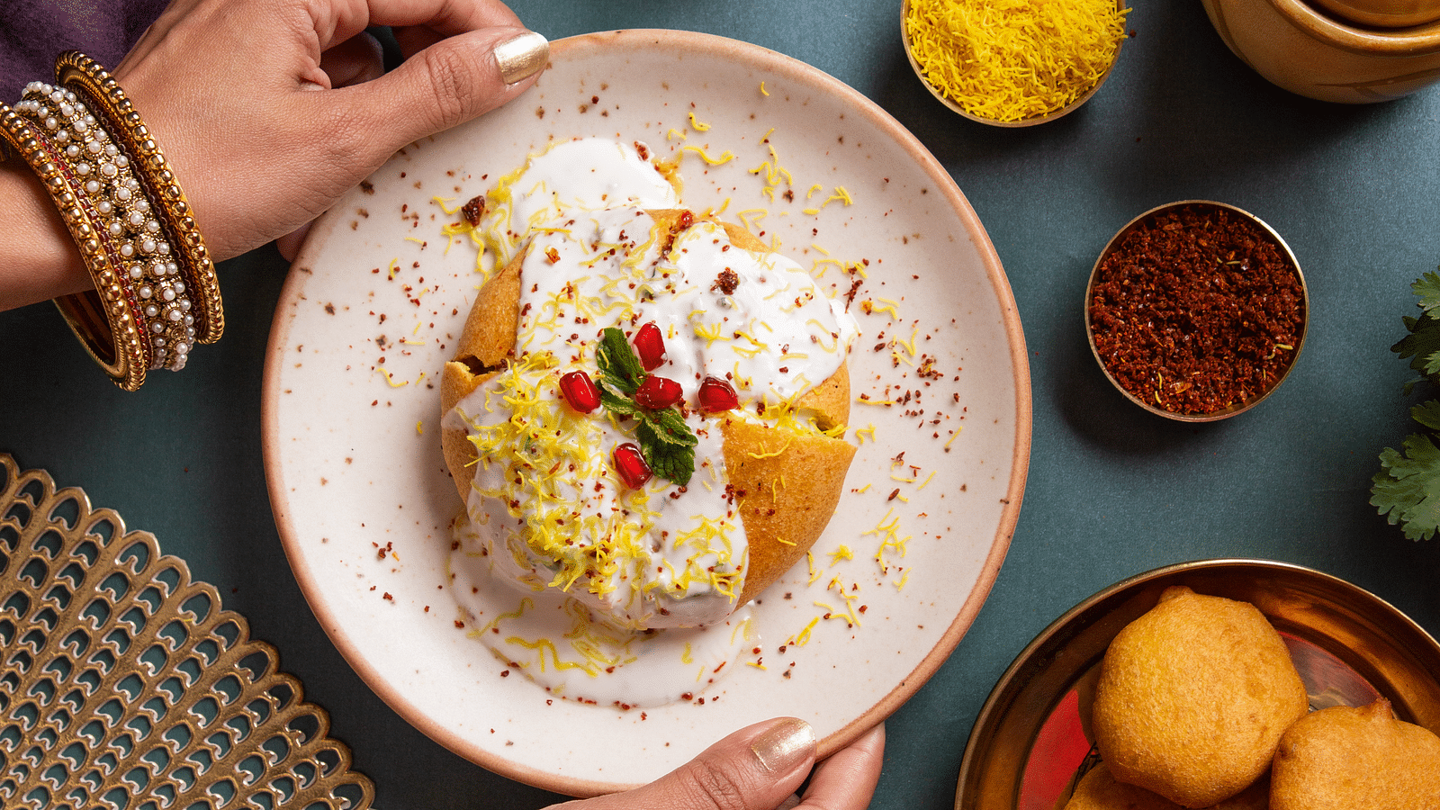 An image of a local fast food called fritters garnished with pomegranate, curd, and mint leaves 