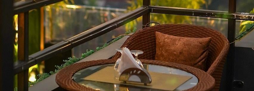 Two chairs facing each other on a terrace with warm lights beside it on a late evening.