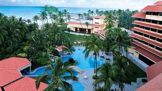 A facade image of The Retreat Hotel and Convention Centre featuring a swimming pool in the hotel premises with greenery around