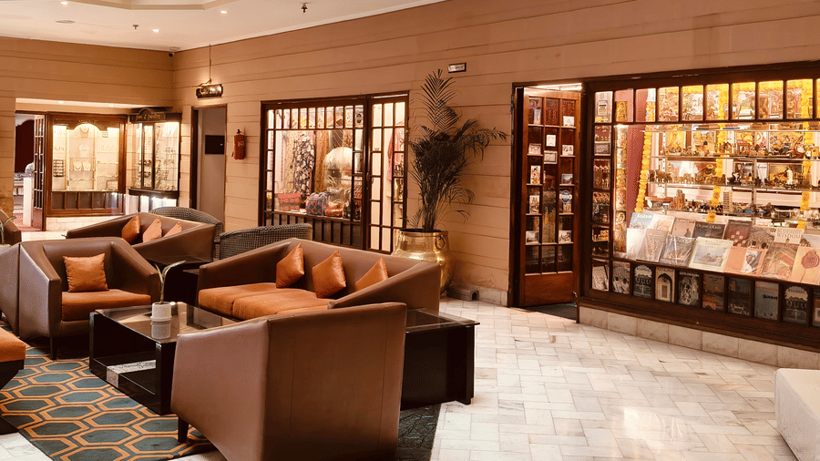A hotel lobby featuring brown armchairs, a coffee table, and a souvenir shop | HHI Varanasi