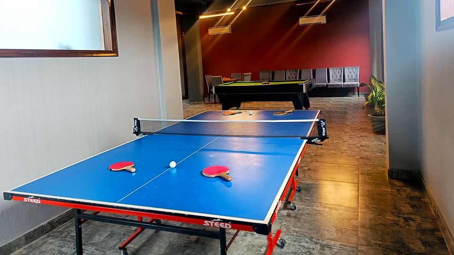 A table tennis setup with a bat and ball on each side, arranged in a brightly lit room at DLS Forest Vines Resort & Spa, Ramnagar (Jim Corbett).