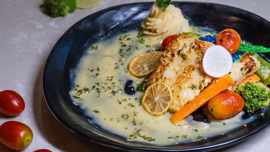 A bowl with a soup-like dish and sliced vegetables.