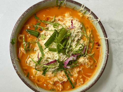 A steaming bowl of Thukpa, a traditional tibetian dish made with vegetables and broth.